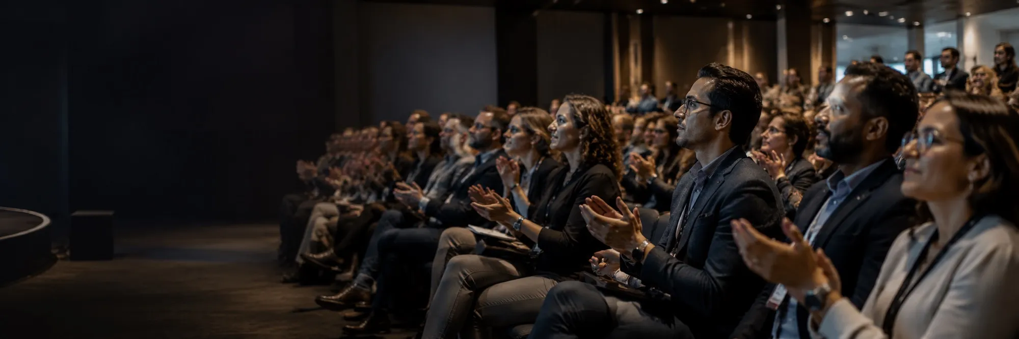 An audience seated in a dark auditorium, applauding.